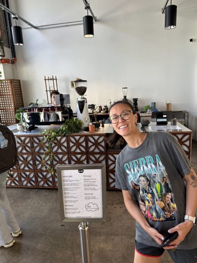 Jackie in front of the barista counter and boondocks coffee.
